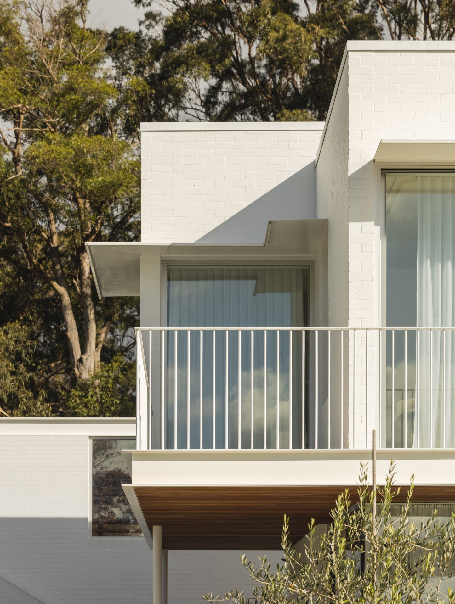 Detail of the white brick facade and balcony at Melody House
